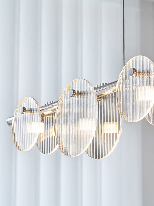 A sleek modern chandelier featuring circular lights that emit a warm, ambient glow, enhancing the elegance of the space.