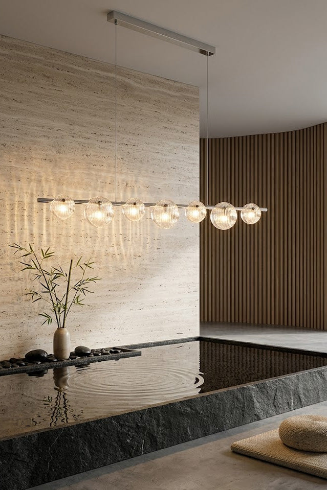 Modern interior with a chandelier, vase with plants, and textured walls.