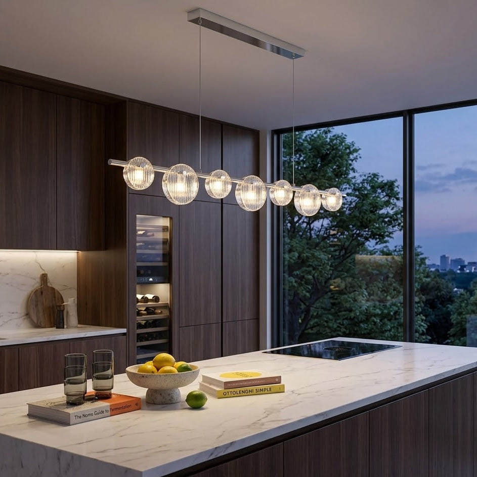 Modern kitchen with a chandelier, marble island, and cityscape view.
