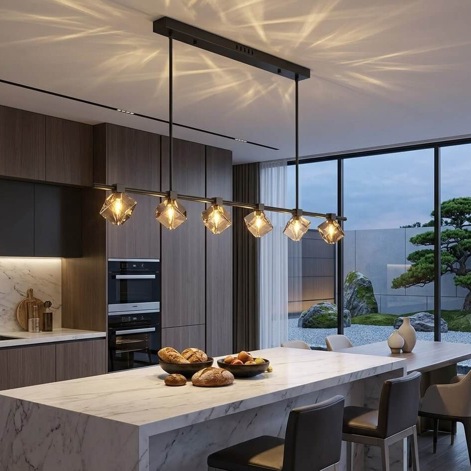 Modern kitchen with marble island, pendant lights, and a view of trees outside.